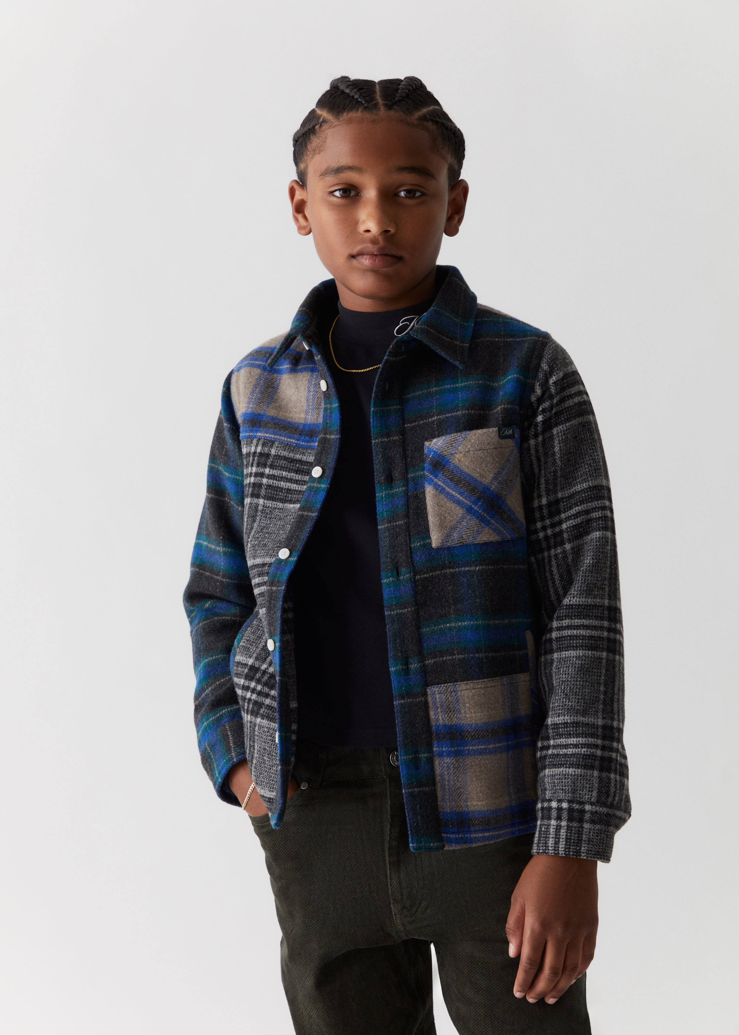 A child wearing a blue and grey color-blocked flannel from the Kith Kids Fall Classics 2023 collection.